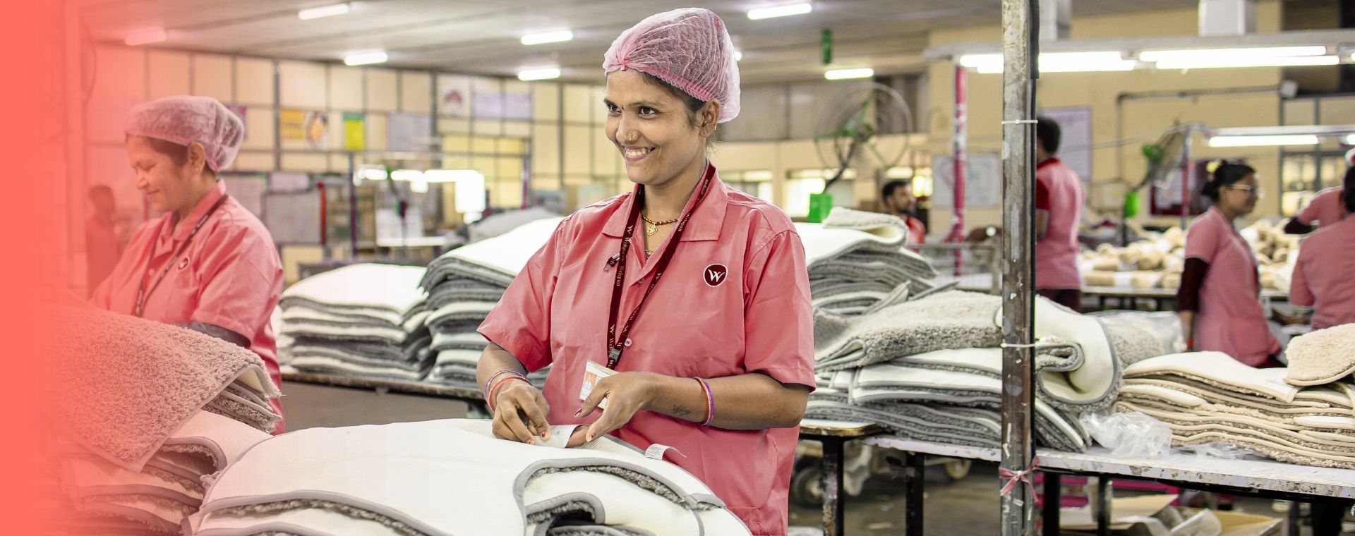 Staff in pink uniforms sorting garments at an Ali & Arwa textile production facility in Dubai